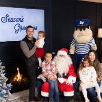 Dad holds sad baby, mom holds sad little girl, and happy boy on Santa's lap